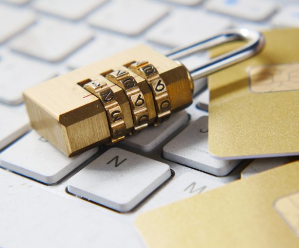 A padlock is placed on a keyboard next to some debit cards to illustrate privacy policy.