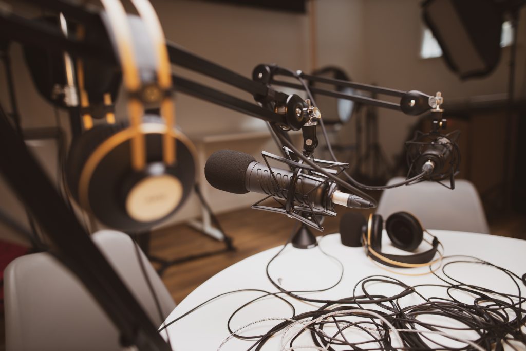 Cables are intertwined on a table, above is a microphone and headphones.